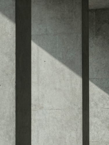 Minimalist editorial photography of architectural concrete columns casting parallel diagonal shadows, cool diffused daylight, 35mm