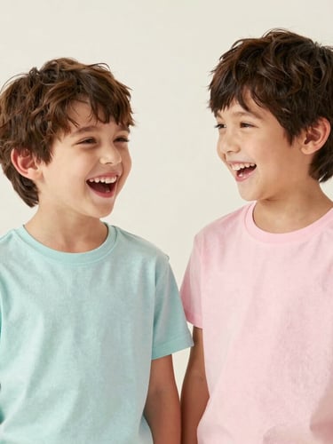 Bright soft studio portrait of two young siblings laughing, wearing clean cotton t-shirts in pastel colors, off-white backdrop, natural daylight, 35mm lens