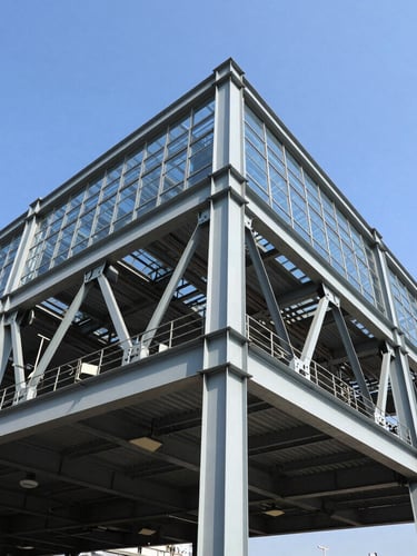 Low-angle architectural photograph of a massive steel structure under a bright blue sky, high-contrast steel beams, industrial precision
