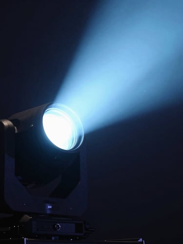 Dramatic close-up of a professional moving head stage light fixture, sharp volumetric light beam in light blue cutting through dark haze, technical details visible, 35mm lens