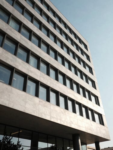 Dignified architectural close-up of a modern secure corporate headquarters in Baghdad, clean lines, high-contrast cinematic daylight, institutional weight.