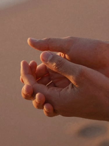 Close-up of two hands gently holding each other, fingers intertwined, warm golden hour sunlight illuminating the skin, shallow depth of field, cinematic 35mm film.