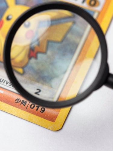 Extreme close-up overhead shot of a vintage Pokémon card corner under a magnification loupe on a bright white studio surface, studio strobe lighting from above, fine print detail and card edge visible in sharp focus