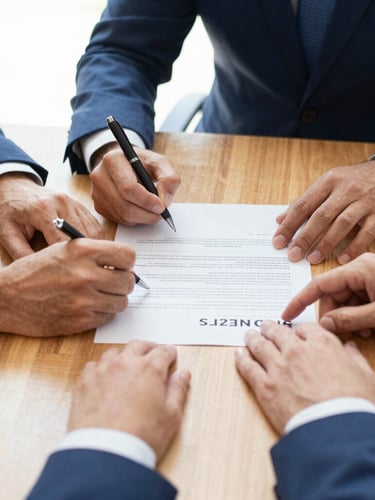 Close-up of friendly hands signing a credit agreement on a clean wooden desk, warm natural daylight, professional cooperative environment