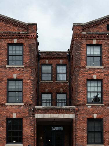 Symmetrical architectural shot of a historic brick industrial building facade in North Charleston, clean lines, overcast light, high contrast.