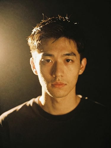 A striking portrait of a modern artist bathed in warm golden-hour backlight against a dark studio background, 35mm photography