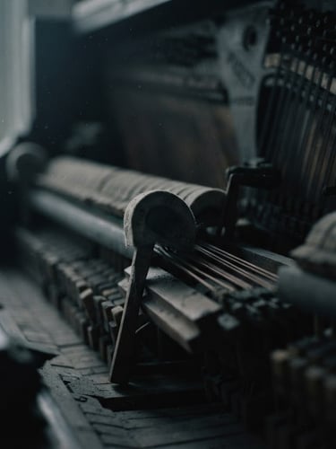 Extreme close-up of the interior of a felted upright piano, soft twilight filtering through dust motes, shallow depth of field, moody film photography, desaturated charcoal tones.