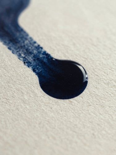 Macro shot of black ink pooling on heavily textured cold-press paper, sharp focus on paper fibers, high-contrast side-lighting, deep ink-blue tones, 35mm photography