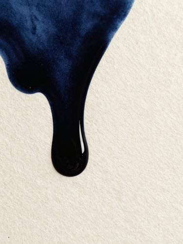 Tight macro shot of deep black ink bleeding into heavy textured cream paper, high-contrast side-lighting, 35mm