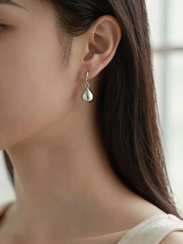 Macro portrait of an elegant woman wearing delicate silver earrings, soft natural window light, warm silver and sophisticated brown tones, shallow depth of field, macro lens, 35mm
