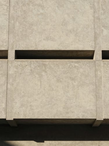 Straight-on architectural detail of a concrete facade with clean geometric lines, soft natural daylight casting subtle shadows, warm editorial style, 35mm