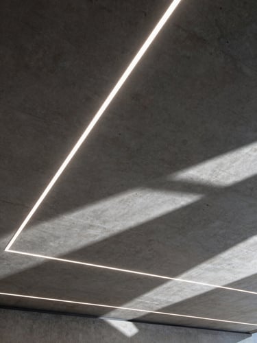 A high-contrast architectural concrete ceiling with precise, sharp linear LED light projections creating dramatic geometric shadows, technical CAD-like layout