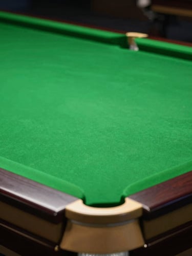 Dramatic close-up of a premium snooker table, rich forest green felt, polished brass pocket corners under moody overhead lighting, shallow depth of field, 35mm