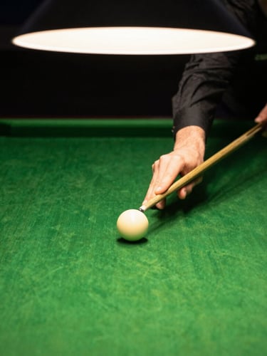 Dramatic close-up of hands tensioning rich green snooker felt over a slate table bed, warm overhead lighting, shallow depth of field, 35mm