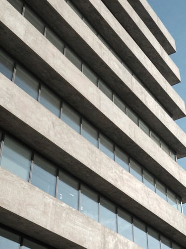 A high-altitude architectural abstract of a modern data center exterior, clean concrete lines and clinical daylight, orthogonal angle.