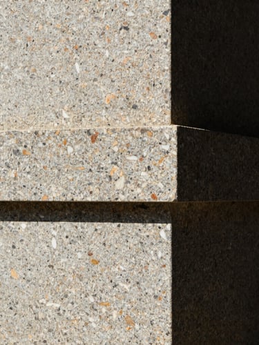Extreme close-up of hand-carved local stone joints on a monolithic granite wall, harsh high-contrast tropical sunlight casting deep shadows, minimalist architectural photography, 35mm lens
