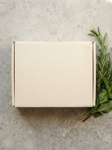 Overhead flat-lay of a discreet unmarked delivery box on a clean stone tabletop, accompanied by fresh rosemary and mint sprigs, soft diffused natural daylight, elegant editorial style