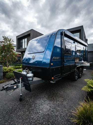 Low-angle heroic shot of a pristine caravan parked in a modern Melbourne driveway, high-contrast overcast daylight reflecting off the polished gelcoat, premium automotive style