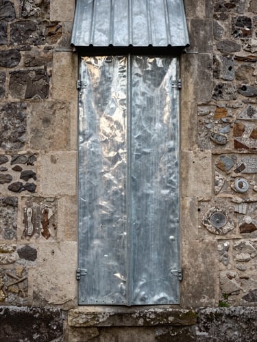 Détail d'une gouttière en zinc parfaitement ajustée sur une corniche ancienne en pierre, reflets métalliques sous un ciel couvert.