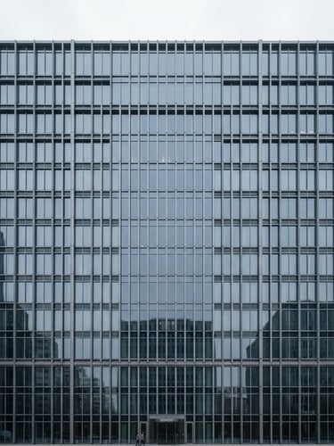 Symmetrical architectural photography of a modern steel and glass skyscraper facade, overcast daylight, desaturated blue and slate tones, sharp focus, 35mm lens