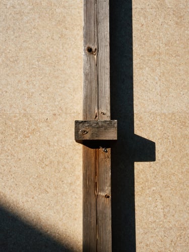 Low-angle architectural film photography of a weathered teak joint with high-contrast afternoon shadows, warm travertine background, 35mm