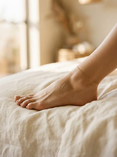 Elegant close-up of a foot arch resting on soft cream linen, warm diffused golden hour window light, shallow depth of field, minimalist luxury spa aesthetic