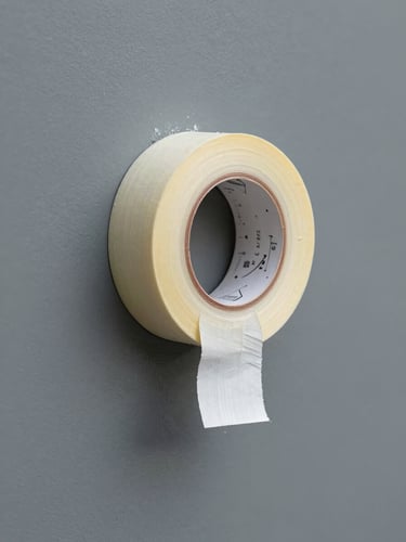 A straight-on macro shot of clean painter's tape being pulled back to reveal a razor-sharp paint line on a slate gray wall, natural bright daylight