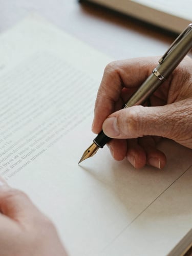 Close-up of hands holding a vintage fountain pen, writing notes in the margin of an archival research document, soft overcast daylight, shallow depth of field.