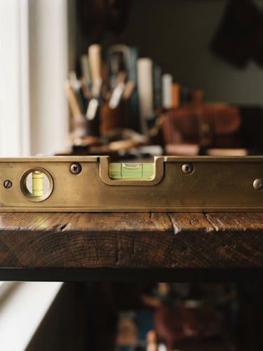 Macro shot of a high-end brass spirit level resting perfectly flat on a dark oak shelf, soft natural window light, shallow depth of field, 35mm