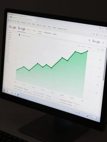 Tight overhead crop of a desktop monitor displaying a Google local search rank tracking dashboard, green upward-trending position lines for 20 keywords across a 90-day timeline, clean dark UI, even screen glow, no people, no branding