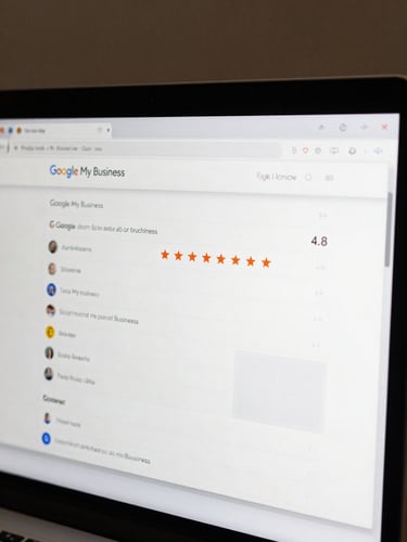 Tight crop of a Google My Business profile panel open in edit mode on a desktop monitor, screen filling the frame edge-to-edge, showing business category fields, review star ratings at 4.8, and a photo upload grid partially filled — clean flat-lit screenshot, no physical environment visible, muted interface colors