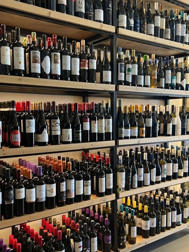 A wide variety of wine bottles displayed on wooden shelves at a wine shop