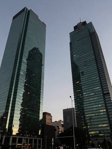 Wide environmental shot of Paseo de la Reforma corporate towers in Mexico City during dusk, high-contrast crisp daylight fading, deep green and obsidian tones reflected in glass facades.
