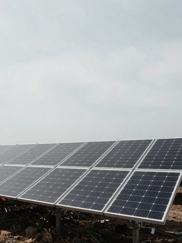 Wide panoramic shot of a solar panel installation site under an overcast sky, desaturated editorial photography, cool daylight, sharp focus, 35mm film