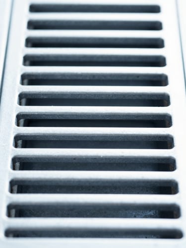 Straight-on symmetrical macro shot of a pristine clean metallic ventilation grate, bright high-key daylight, clinical cool blue tones, sharp focus.