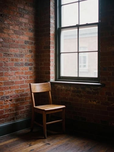 A quiet, empty corner of an old brick storefront church, a single wooden chair cast in deep shadows by soft overcast daylight streaming through a dusty window, 35mm