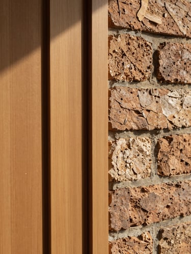 Intimate detail crop of warm cedar wood panels meeting hand-laid historic brick, soft morning light casting gentle shadows, architectural texture.
