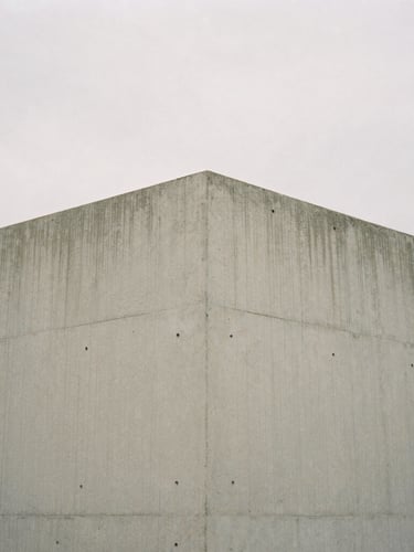 Minimalist editorial photography of a concrete architectural corner, soft diffused overcast daylight, muted natural tones, medium format film, quiet composition, 80mm.