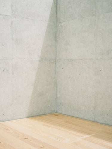 A minimalist concrete wall corner meeting a light oak floor, soft diffused overcast daylight casting subtle shadows, quiet architectural composition, medium format film look.