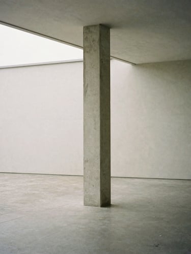 A solitary concrete column standing in a wide gallery space, soft diffused overcast daylight from a high window, minimalist editorial photography, 80mm.