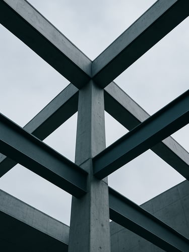 Low-angle architectural shot of structural concrete and steel beams against a cool overcast sky, sharp geometric lines and shadows, 35mm lens