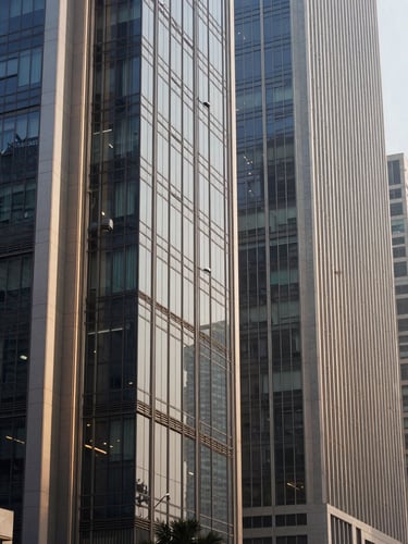 Wide panoramic architectural detail of a modern financial district in New Delhi, clean glass facades reflecting soft morning light, editorial corporate photography.