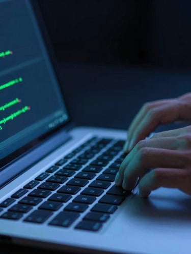 Dynamic close-up of a professional developer coding on a modern laptop, hands on keyboard, screen glowing with neon blue and green code, high-contrast studio lighting, 35mm photography