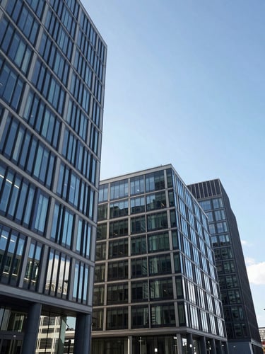 Architectural wide-angle shot of Cologne office district in crisp daylight, modern glass facades reflecting a clear blue sky, clean lines, professional atmosphere.