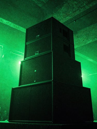 A towering speaker stack inside a raw concrete warehouse, backlit by intense acid green strobe lights, low-angle shot, gritty grain.