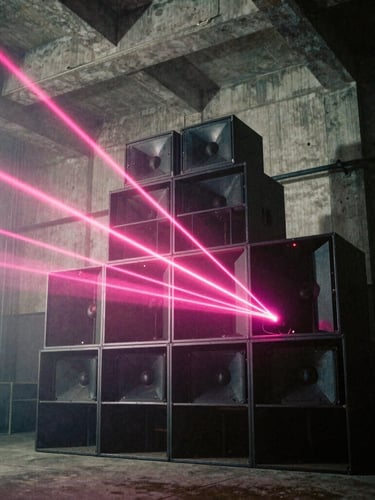 Low-angle wide shot of a towering custom speaker array in a raw concrete warehouse, sharp hot pink lasers cutting through thick fog, heavy film grain