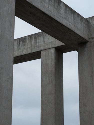 Tight, abstract structural crop of modern architectural concrete columns meeting under a diffused, cool overcast sky, emphasizing structural integrity and geometric precision.