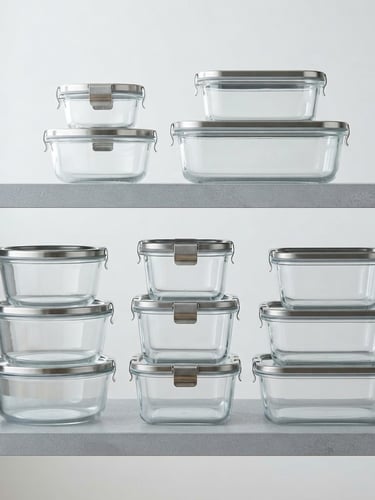 Pristine glass kitchenware containers stacked neatly on a cool gray shelf, bright studio lighting with crisp reflections