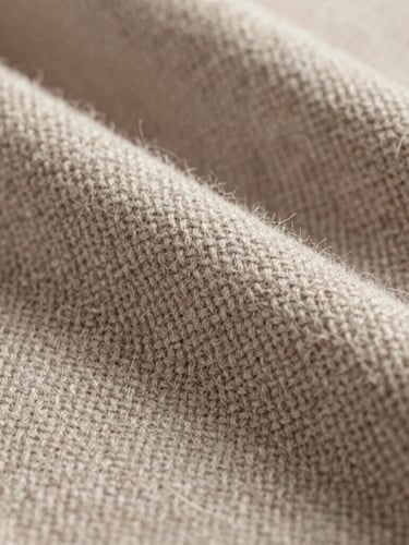 Macro close-up of premium woven wool fabric, showing the intricate twill pattern and soft fibers in warm taupe and bone white, diffused studio lighting, shallow depth of field.
