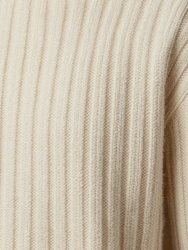 Extreme close-up macro shot of a cream-colored luxury wool sweater, showcasing intricate ribbed knit textures and fine-gauge yarn stitches under soft diffused studio lighting.